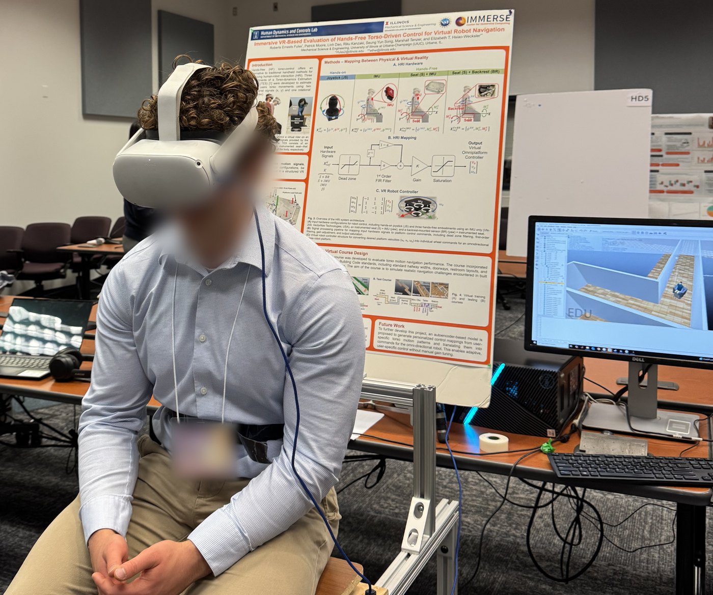 A participant seated on the earlier-prototype TES wearing a VR headset, with the IMMERSE poster behind them and a monitor at right showing the CoppeliaSim navigation course. The participant's face and name badge are blurred.